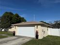 Side angle view of a attached two-car garage with adjacent green lawn and manicured shrubbery at 11708 Nicklaus Cir, Tampa, FL 33624