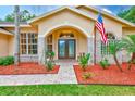 Inviting front entrance with double doors, brick accents, mulch beds and lush greenery at 12302 Knight Pl, Thonotosassa, FL 33592