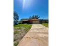 Brick home with an attached garage, spacious driveway, and green front lawn at 1850 Oklahoma Ne Ave, St Petersburg, FL 33703