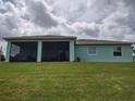 View of the house from the backyard showcasing the screened-in lanai and lush green lawn at 3190 Darius Ave, North Port, FL 34288