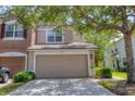 Beige two-story townhome featuring an attached two-car garage and well-maintained landscaping at 4920 Pond Ridge Dr, Riverview, FL 33578