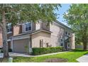 Beige townhome featuring an attached two-car garage and well-maintained landscaping at 4920 Pond Ridge Dr, Riverview, FL 33578