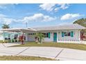 Inviting single-story home features a carport, turquoise shutters, tidy landscaping and charming curb appeal at 6801 Clark St, Hudson, FL 34667