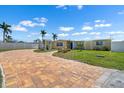 Charming yellow home with a brick driveway, palm trees, a blue door, and well-maintained lawn at 109 Carmelina St, Ruskin, FL 33570