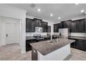 Modern kitchen featuring dark cabinets, a large island, and stainless steel appliances at 11820 Sunburst Marble Rd, Riverview, FL 33579