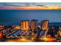 Aerial view showcasing beachfront condo towers, parking, and a pool at dusk at 17920 Gulf Blvd # 2004, Redington Shores, FL 33708