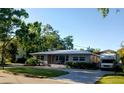Charming single-story home with vibrant orange door, landscaped lawn, and paved driveway at 3217 W Lawn Ave, Tampa, FL 33611