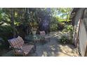 Outdoor patio featuring a glass table with comfortable striped chairs surrounded by lush plants and greenery at 3527 Greenglen Cir, Palm Harbor, FL 34684
