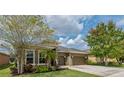 Attractive home with a well-maintained lawn, mature trees, and a two-car garage at 4839 Pointe O Woods Dr, Wesley Chapel, FL 33543