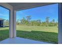 An outdoor back porch with a view of an expansive lawn and lush greenery under a clear, sunny sky at 5325 Thistle Field Ct, Wesley Chapel, FL 33545