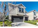 Townhome showcasing a two-car garage, stucco facade, well-kept landscaping, and a modern architectural style at 6827 Citrus Creek Ln, Tampa, FL 33625
