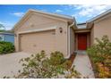 Home exterior with a two-car garage, red front door, and landscaped yard at 8529 Hunters Fork Loop, Ruskin, FL 33573
