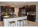 Modern kitchen with dark wood cabinets, stainless steel appliances, granite countertops, and an island with barstool seating at 12957 Wildflower Meadow Dr, Riverview, FL 33579
