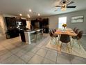 Open-concept kitchen and dining area features dark cabinets, stainless appliances, island seating, and a stylish dining set at 12957 Wildflower Meadow Dr, Riverview, FL 33579