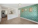 Open-concept living area with hardwood floors, modern kitchen, and decorative wallpaper accent wall at 1300 37Th S St, St Petersburg, FL 33711