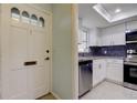 Bright kitchen with stainless appliances, granite countertops, dark backsplash, and white cabinets by a front door at 1466 Normandy Park Dr # 4, Clearwater, FL 33756