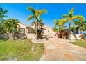 Charming home featuring a well-manicured lawn, tropical palm trees, and a decorative stone walkway at 151 Harrisburg St, Port Charlotte, FL 33954