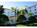 Well-manicured landscaping surrounds a white condo building with red tile roof and white trim, providing an elegant and inviting facade at 1860 N Fort Harrison Ave # 301, Clearwater, FL 33755