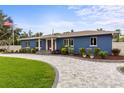 Beautifully landscaped front yard with a circular driveway leading to a well-maintained blue home with an American flag at 301 71St S St, St Petersburg, FL 33707