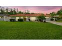 Inviting single-story home boasts a red tile roof, a well-manicured lawn, and a picturesque sunset backdrop at 4555 Debbie Ln, Lutz, FL 33559