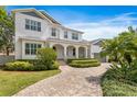 Charming two-story home with a brick driveway, arched porch, and well-maintained front yard with lush greenery at 47 Martinique Ave, Tampa, FL 33606