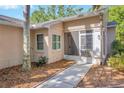 Inviting entryway featuring a tiled walkway, screened porch, and neutral-colored exterior at 5245 Lochmead Ter, Zephyrhills, FL 33541