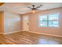 Bright living room featuring hardwood floors, a ceiling fan, and a large window providing ample natural light at 7827 Crosier Ct, New Port Richey, FL 34653