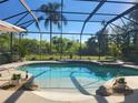 A stunning screened pool with a jacuzzi is surrounded by lush greenery, rocks and potted plants at 21654 Draycott Way, Land O Lakes, FL 34637