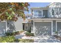 Close up of the townhome featuring a one-car garage, neutral paint, and mature trees providing shade at 2211 Kings Palace Dr, Riverview, FL 33578