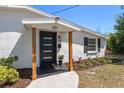 Close up of home's modern entrance features a new black door and stylish wooden supports at 331 Barbara Cir, Belleair, FL 33756