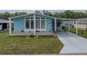 Attractive light blue home boasting lush landscaping, covered parking, and a welcoming front porch at 35026 Colony Hills Dr, Zephyrhills, FL 33541