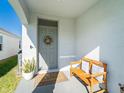 Covered front porch featuring a charming bench and decorated front door at 5571 Birch River Trl, Wesley Chapel, FL 33545