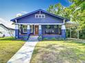 Charming blue two-story home with a manicured front yard, inviting porch, and convenient carport at 714 W Peninsular St, Tampa, FL 33603