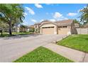 Spacious home featuring a three-car garage, a long driveway, and verdant lawn at 9905 Woodbay Dr, Tampa, FL 33626