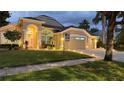 Beautiful home exterior featuring a well manicured lawn, landscape lighting, and a three car garage at 9905 Woodbay Dr, Tampa, FL 33626