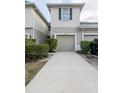 Exterior view of a beige two-story townhome with a one-car garage and a long driveway at 10943 Verawood Dr, Riverview, FL 33579