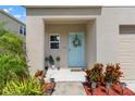 Inviting front porch with a teal door, lovely wreath, and neat landscaping leading to the entrance at 12856 French Market Dr, Riverview, FL 33579