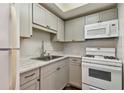 Efficient kitchen featuring white appliances, gray cabinets, and a stylish backsplash at 1900 59Th N Ave # 108, St Petersburg, FL 33714