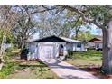 Beautiful white single-story home with a garage, complemented by a green lawn and shady mature trees at 2004 Nobleton Ave, Spring Hill, FL 34608