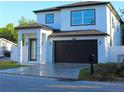 Side view of a modern two-story home featuring a black garage door, white exterior, and well-manicured lawn at 2211 E 28Th Ave, Tampa, FL 33605