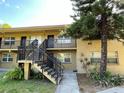 Two-story apartment building featuring exterior stairs and a mature tree in a landscaped yard at 2500 Harn Blvd # B11, Clearwater, FL 33764
