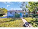 Charming exterior of a well-maintained home with a vibrant lawn, landscaped garden, and inviting blue front door at 2700 56Th S St, Gulfport, FL 33707