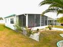 Angle view of a mobile home highlighting a large, screened lanai and lush landscaping at 5244 Betty St, Zephyrhills, FL 33542