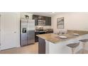 Bright kitchen featuring stainless steel appliances, dark cabinetry, granite countertops, and a breakfast bar at 1210 Cape Chestnut Pl, Ruskin, FL 33570