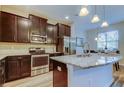 Modern kitchen with dark wood cabinets, stainless steel appliances, granite countertops, and island seating at 13217 Canopy Creek Dr, Tampa, FL 33625