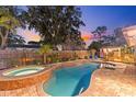Backyard oasis with a sparkling pool, hot tub, and fenced-in yard and a wooden deck with covered outdoor kitchen at 1330 Gulfview Woods Ln, Tarpon Springs, FL 34689