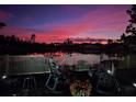 Serene backyard view featuring a waterfront view, a fire pit, rocking chairs, and a pink sky at 21832 Crest Meadow Dr, Land O Lakes, FL 34637