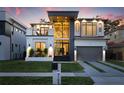 Stunning modern home with clean lines, a balcony, manicured lawn, and two-car garage at dusk at 3105 S Schiller St, Tampa, FL 33629