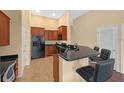 Kitchen featuring wood cabinets, a breakfast bar with seating, a black refrigerator, and tile flooring at 5714 Kingletsound Pl, Lithia, FL 33547