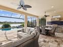 An expansive outdoor patio with ceiling fans, comfortable furniture, lake view and an outdoor kitchen at 11248 Juglans Dr, Odessa, FL 33556